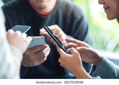 Group Of Young People Using And Looking At Mobile Phone Together