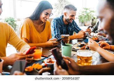 Group of young people using smart phone mobile sitting at bar restaurant - Addicted teenagers by technology watching cellphones together - Happy friends ordering food by phone - Food and tech concept