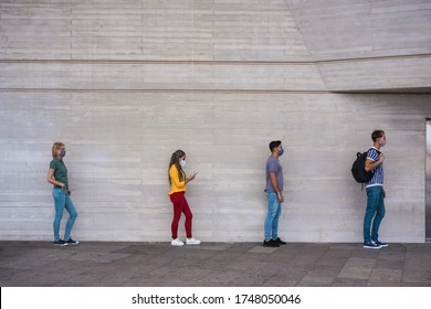 Group of young people waiting for going inside a shop market while keeping social distance in a line during coronavirus time - City outbreak lifestyle, protective face mask and spread virus prevention - Shutterstock ID 1748050046