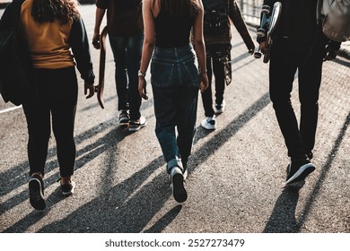 Group of young people walking together, carrying skateboards. Diverse group of friends, casual clothing, skateboards, urban setting. Youth, skateboards, and friendship in the city. - Powered by Shutterstock