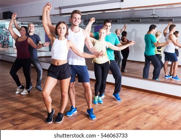 Group Of Young Positive People Learning Salsa At Dance Class