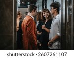 A group of young professionals engaged in casual conversation inside a modern elevator. The setting reflects a contemporary urban lifestyle and social interaction among colleagues.