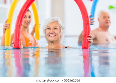 Group  Or Young And Senior People In Aquarobic Fitness Swimming Pool Exercising With  Pool Noodle