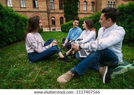 Group of young smile students sitting on the grass at talking at campus