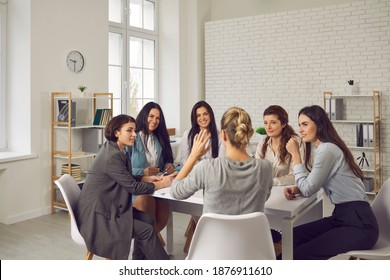 Group of young smiling businesswomen office workers or company employees sitting in circle at desk in modern loft office interior and planning projects together. Women working in company concept