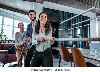 Group of young smiling office workers playing tug of war. Business advantage concept - Powered by Shutterstock