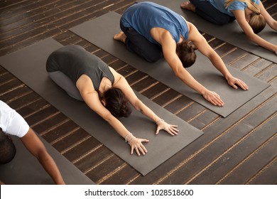 Group Of Young Sporty Afro American And Caucasian People Practicing Yoga Lesson Stretching In Child Exercise, Balasana Pose, Working Out, Indoor, Studio Top View. Healthy Lifestyle Concept