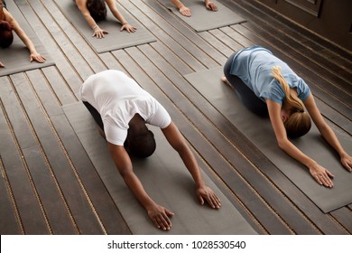 Group Of Young Sporty Afro American And Caucasian People Practicing Yoga Lesson Stretching In Child Exercise, Balasana Pose, Working Out, Indoor, Studio Top View. Healthy Lifestyle Concept