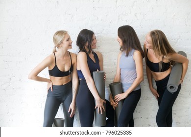 Group Of Young Sporty Girls With Fitness Mats Talking. Chatting While Having A Break, Exchanging News, Sharing Diet And Exercise Tips, Making True Friends In Yoga Community, Studio