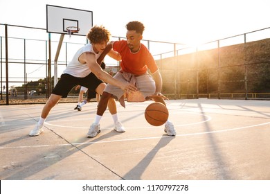 Group of young sporty multiethnic men basketball players playing basketball at the sport ground - Powered by Shutterstock