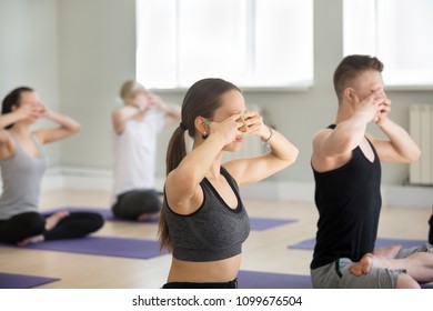 Group Of Young Sporty People Practicing Yoga Lesson, Doing Bhramari Pranayama Exercise, Humming Bee Breathing, Sukhasana Pose, Working Out, Indoor Full Length, Students Training In Sport Club, Studio