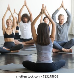 Group Of Young Sporty People Practicing Yoga Lesson With Instructor, Sitting In Sukhasana Exercise, Easy Seat Pose, Friends Working Out In Club, Rear View At The Teacher, Indoor Full Length, Studio 