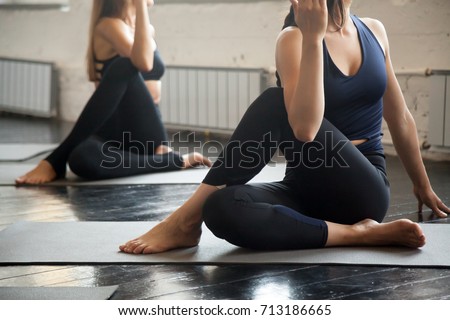 Group of young sporty people practicing yoga lesson with instructor, sitting in Half lord of the fishes exercise, working out indoor, close up image, studio. Wellbeing, wellness concept 