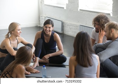 Group of young sporty smiling people sitting on the floor, yoga practitioners talking after lesson, friends having rest before fitness class, students meeting in the gym, indoor full length, studio  - Powered by Shutterstock