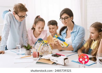 A group of young students are engaged in a STEM class, working together to build a robot. A teacher guides them, while they follow instructions and use their creativity to solve problems. - Powered by Shutterstock