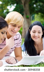 group of young students studying computer on grass