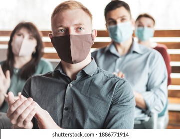 Group Of Young Successful People Wearing Masks On Their Faces Sitting In The Audience Hall And Listening To The Speaker - Applause During A Business Meeting - Work Colleagues Sitting At A Conference