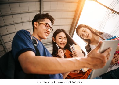 A group of young or teen asian student in university smiling and reading the book and look at the tablet or labtop computer in summer holiday. - Shutterstock ID 759764725