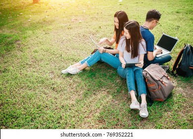 A Group Of Young Or Teen Asian Student In University Smiling And Reading The Book And Look At The Tablet Or Laptop Computer In Summer Holiday.