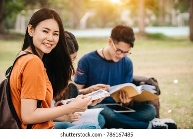 A Group Of Young Or Teen Asian Student In University Smiling And Reading The Book And Look At The Tablet Or Laptop Computer In Summer Holiday.