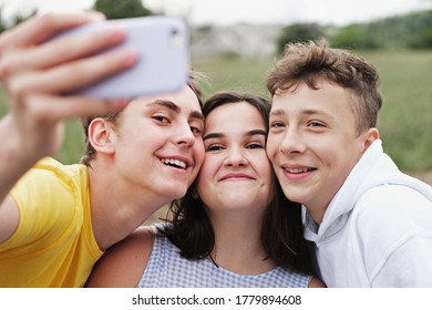 Gruppe junger Teenagerfreunde, die sich auf einem Smartphone mit ihren Köpfen im Freien, die an der Kamera grinsend grinsend auf der Kamera stehen, selbst auf ein Handy setzen