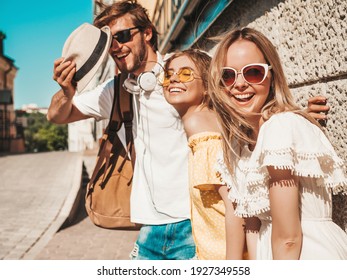 Group Of Young Three Stylish Friends Posing In The Street. Fashion Man And Two Cute Female Dressed In Casual Summer Clothes. Smiling Models Having Fun In Sunglasses.Cheerful Women And Guy Outdoors