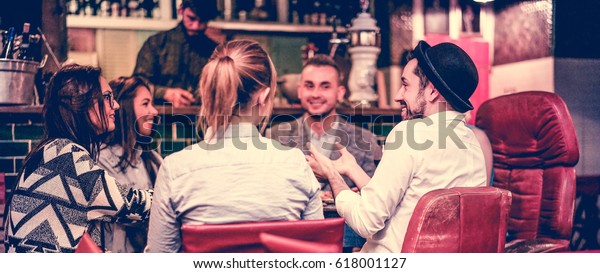 Group of young trendy friends chatting and\
laughing together inside cocktail fashion bar - Cheerful people\
having fun doing pre dinner appetizer - Focus on right man face -\
Vintage filter