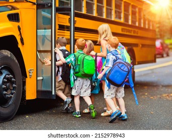 A group of young unidentifiable children getting on the schoolbus