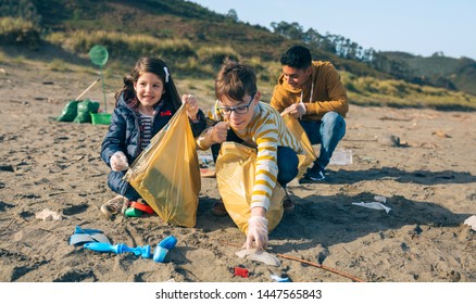 Group Of Young Volunteers Picking Up Trash On The Beach