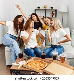 Group Of Young Woman Friends Having Party Eating Italian Pizza And Singing Song At Home.