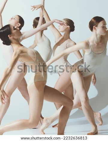 Group of young women, ballerinas dancing, performing isolated over grey studio background. Tender shadows. Concept of art, beauty, aspiration, creativity, classic dance style, elegance