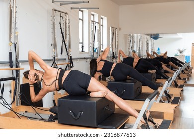 Group of young women exercising on pilates reformers beds - Shutterstock ID 2316877613