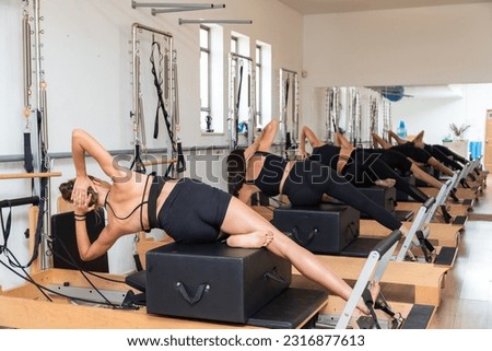 Group of young women exercising on pilates reformers beds