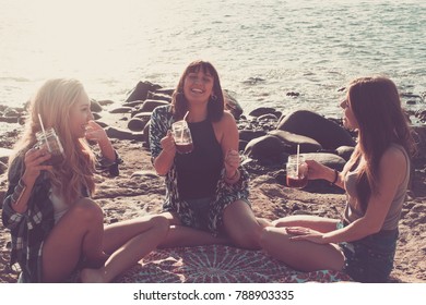 Group Of Young Women Friend Drinking Together A Fruit Juice On A Rock Beach In Tenerife. Relationship For A Team To Ejoy The Vacation And Happiness.