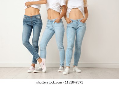 Group Of Young Women In Jeans Near Light Wall