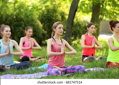 Group of young women practicing yoga outdoors - Powered by Shutterstock