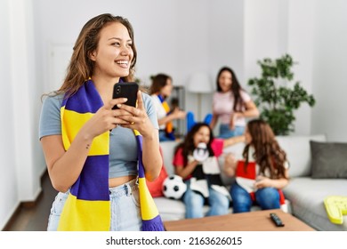 Group Of Young Women Watching And Supporting Soccer Match. Hispanic Woman Smiling Happy And Using Smartphone At Home.