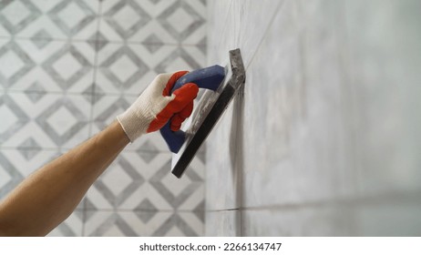 Grout in the bathroom. Black grout for tiles. laying ceramic tiles. Tilers fill the spaces between tiles with a rubber trowel.