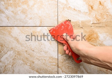 Grouting ceramic tiles on the wall. Applying fugue on ceramic tiles with a spatula.