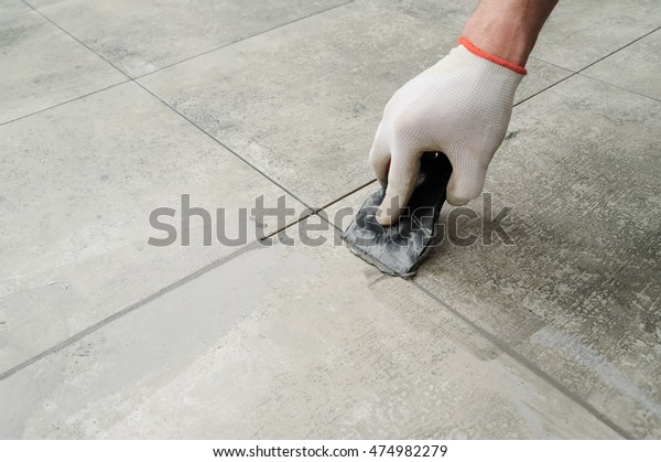 Grouting ceramic tiles. Tilers filling the\
space between tiles using a rubber\
trowel.