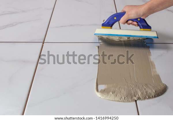 Grouting tiles with a rubber\
trowel