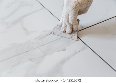 Grouting tiles seams with a rubber trowel. - Shutterstock ID 1442516372