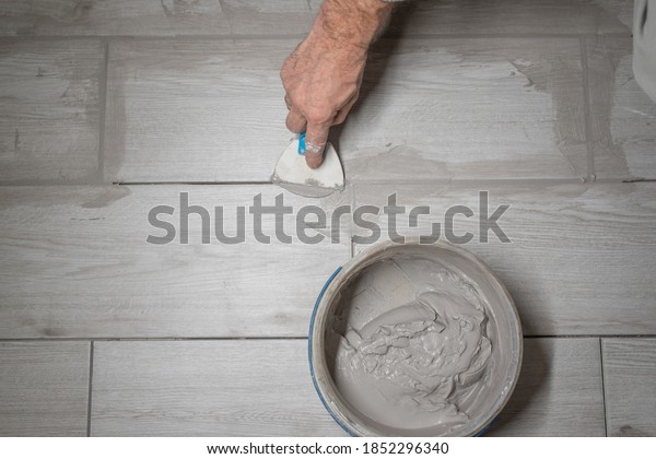 Grouting tiles seams with a rubber trowel.
worker applies grout whit rubber trowel
tiles