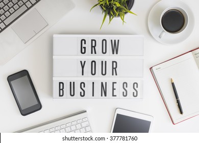 Grow your business words on office table with computer, coffee, notepad, smartphone and digital tablet