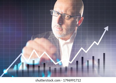 Growing Chart. Man Uses A Financial App On His Tablet. Grown Man Shows Growing Charts. Financier On A Dark Background Next To Charts. Analyst Predicts The Growth. Concept - Positive Outlook.