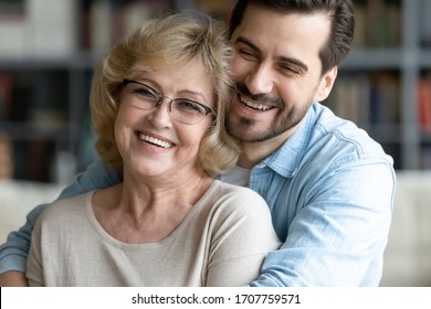 Grown up son hugs elderly mother laughing joking enjoy funny time together. Adult child visit mom at home, warm relations, familial bond strong connection between family members concept close up image