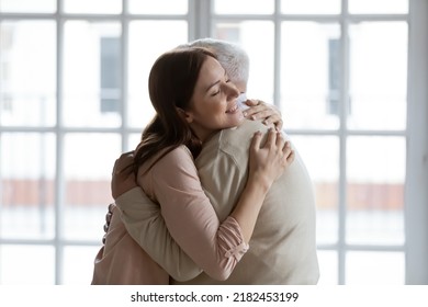 Grownup daughter straining to heart dear senior dad meeting after long time separation. Tender young woman adult grandkid cuddling with warmth elderly man grandfather greeting with birthday father day