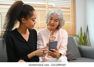 Grownup Daughter Teaching Interested Retired Mother Using Social Networks On Smart Phone. Elderly, Technology Concept