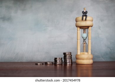 Growth of income over time and return on investment concept. Selective focus image of businessman sit on hourglass with stack of coins. Copy space for text - Shutterstock ID 2017454978