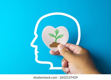 Growth mindset and personal development concept.A small tree growing in a heart shape being placed into a brain,representing positive thinking,self-improvement,developing new skills.